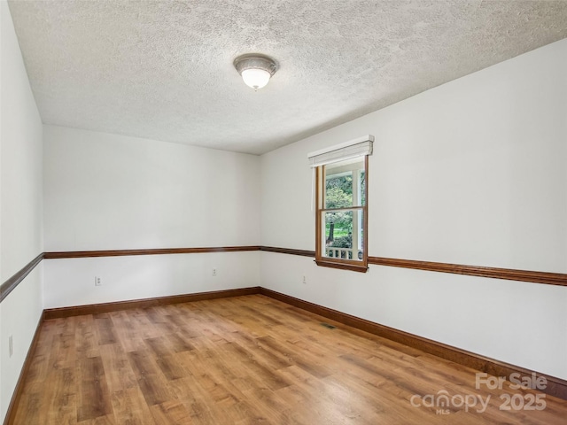 empty room featuring baseboards, wood finished floors, and a textured ceiling