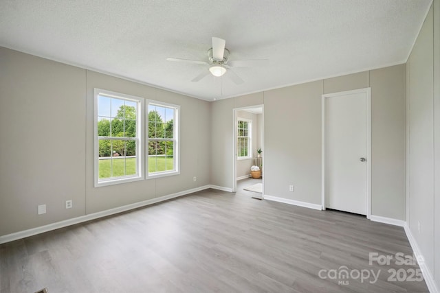 empty room with wood finished floors, ceiling fan, baseboards, and a textured ceiling