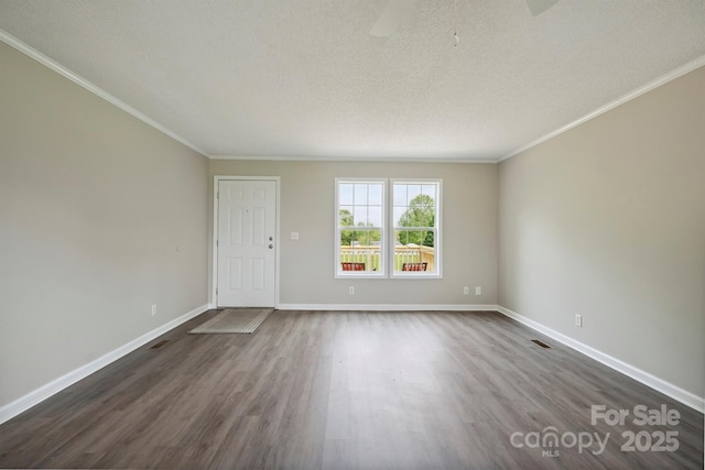 unfurnished room featuring crown molding, a textured ceiling, dark wood-style flooring, and baseboards