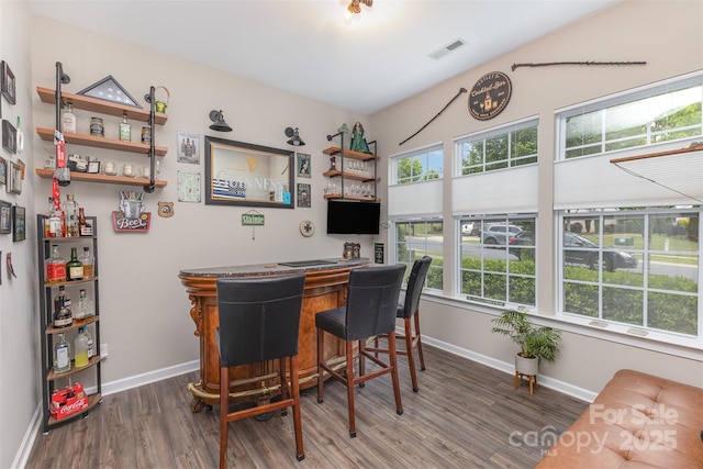 bar with visible vents, wood finished floors, a wealth of natural light, and a bar