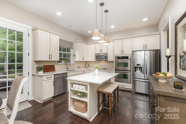 kitchen with a sink, tasteful backsplash, appliances with stainless steel finishes, light countertops, and a breakfast bar area