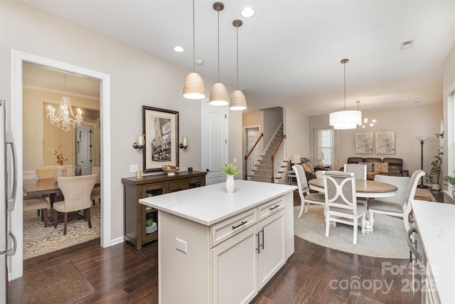 kitchen featuring white cabinets, an inviting chandelier, light stone countertops, pendant lighting, and dark wood-style flooring