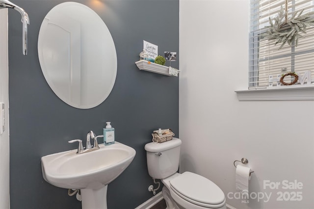 bathroom featuring baseboards, a sink, and toilet