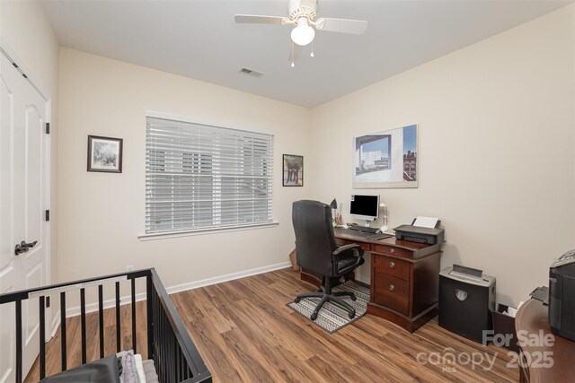 home office featuring wood finished floors, visible vents, a ceiling fan, and baseboards