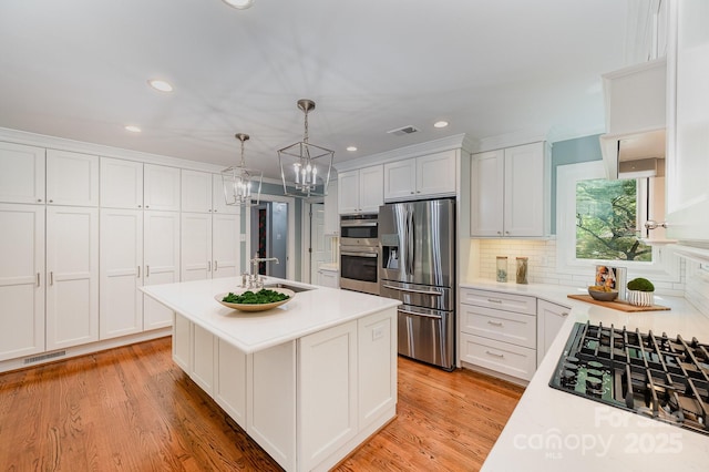 kitchen with light countertops, stainless steel fridge, visible vents, and black gas stovetop