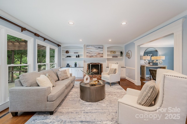 living room with a fireplace, wood finished floors, recessed lighting, and ornamental molding