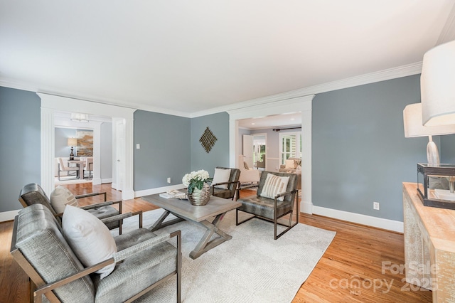 living room with light wood finished floors, baseboards, and ornamental molding