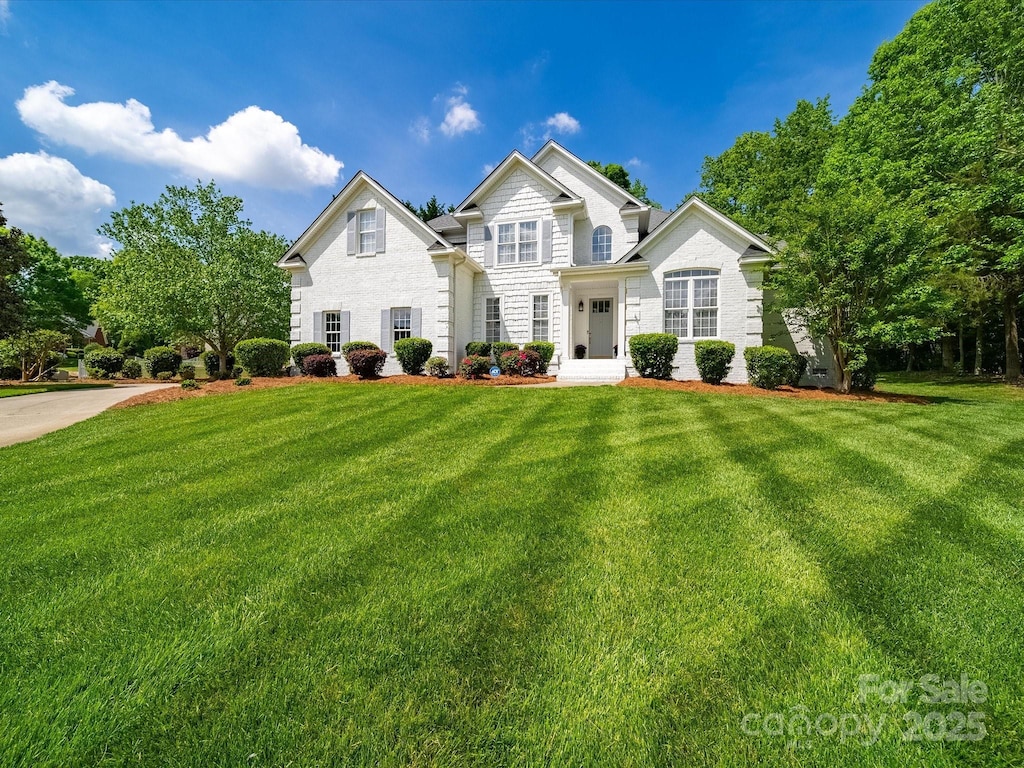 traditional-style home featuring brick siding and a front lawn