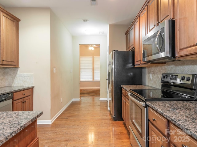 kitchen featuring light wood finished floors, brown cabinets, stainless steel appliances, and baseboards