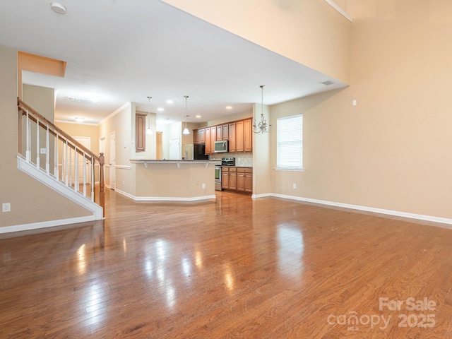 unfurnished living room featuring light wood finished floors, recessed lighting, a notable chandelier, stairs, and baseboards