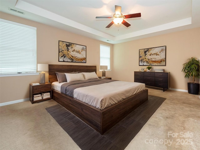 bedroom featuring visible vents, baseboards, a tray ceiling, and carpet floors