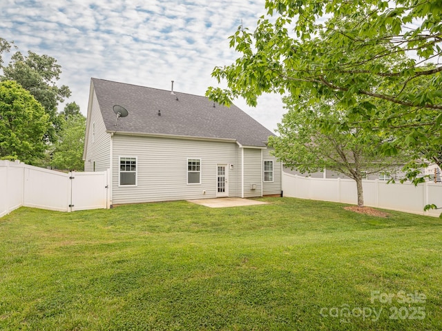 rear view of house featuring a patio, a yard, a fenced backyard, and roof with shingles