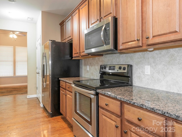 kitchen featuring light wood-style floors, ceiling fan, brown cabinetry, backsplash, and appliances with stainless steel finishes