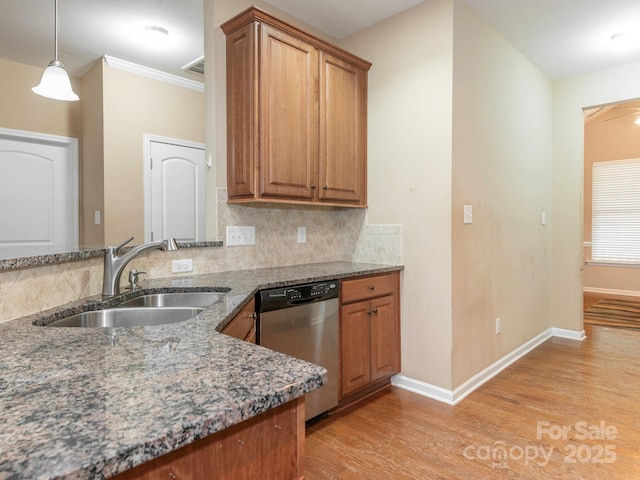 kitchen with brown cabinetry, stainless steel dishwasher, light wood-style floors, and a sink