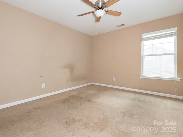 carpeted empty room with ceiling fan, visible vents, and baseboards