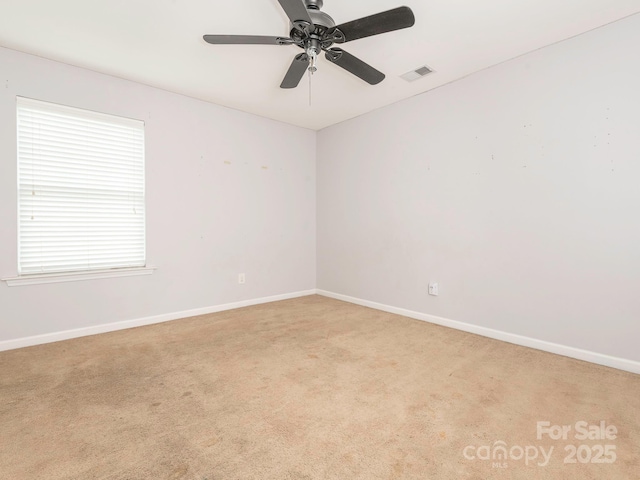 spare room featuring light colored carpet, visible vents, and baseboards