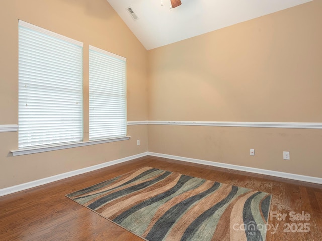 unfurnished room with baseboards, visible vents, wood finished floors, and lofted ceiling