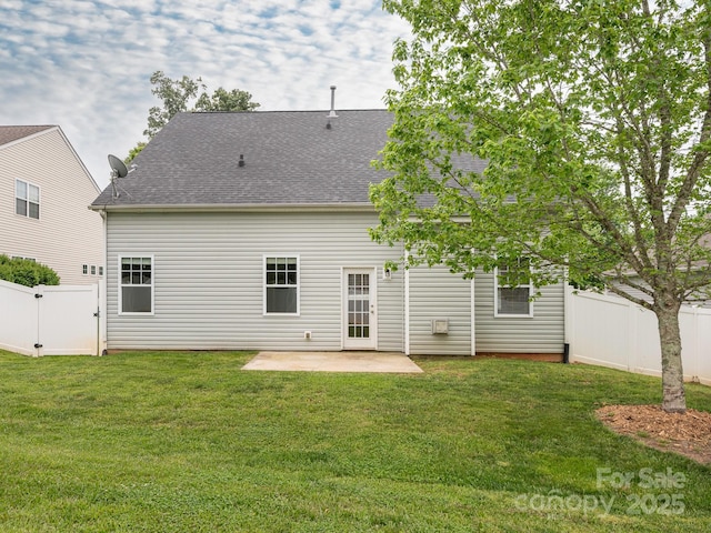 rear view of property featuring a shingled roof, a patio area, a fenced backyard, a gate, and a lawn