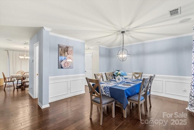 2739 Golden Rose Ln, Charlotte, NC 28216 - dining area featuring a chandelier, wainscoting, dark wood finished floors, and a decorative wall