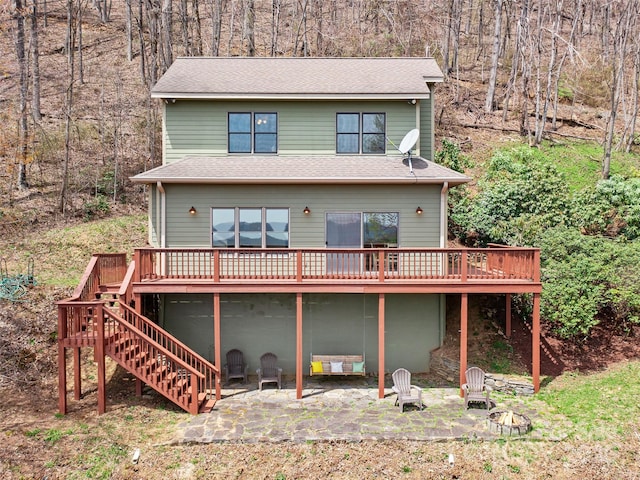 rear view of property with a wooden deck, stairway, a patio area, and a shingled roof