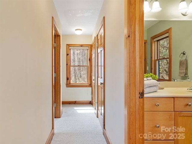 hall featuring light carpet and baseboards