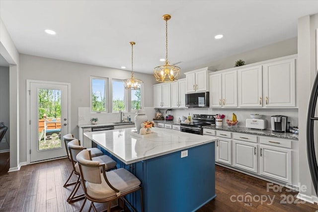 kitchen with electric range, backsplash, white cabinetry, and a chandelier