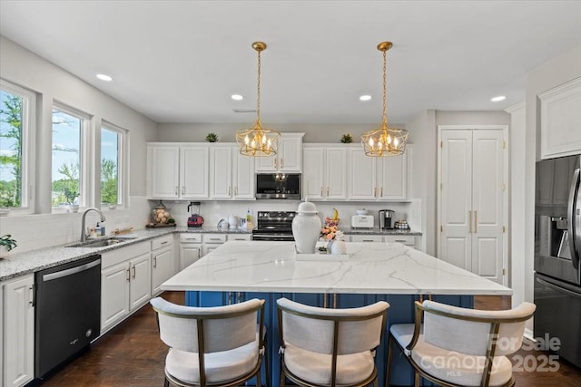 kitchen with a sink, white cabinetry, decorative backsplash, a kitchen island, and appliances with stainless steel finishes