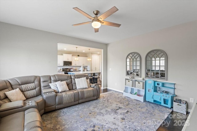 living room with wood finished floors, baseboards, and ceiling fan