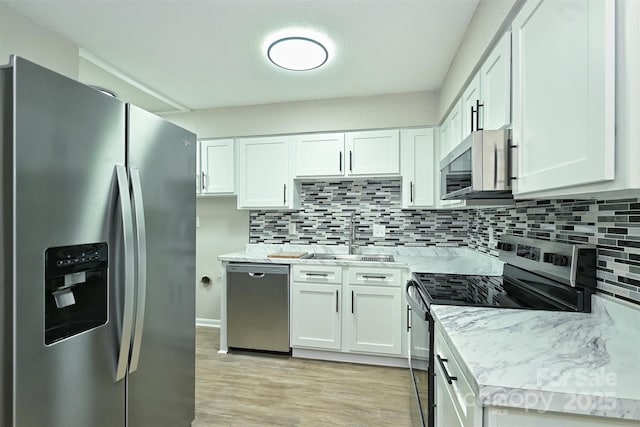 1931 Mereview Ct Unit 46, Charlotte, NC 28210 - kitchen featuring appliances with stainless steel finishes, backsplash, white cabinets, and light wood-type flooring