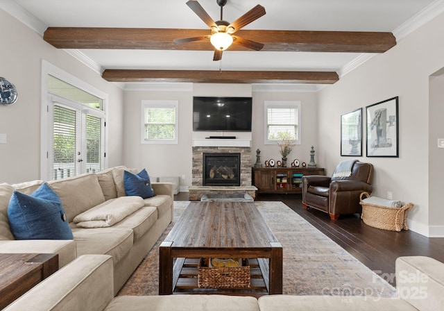 living room featuring beam ceiling, ceiling fan, a stone fireplace, baseboards, and dark wood finished floors