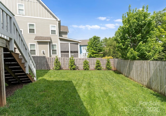 view of yard with stairway, a sunroom, and a fenced backyard