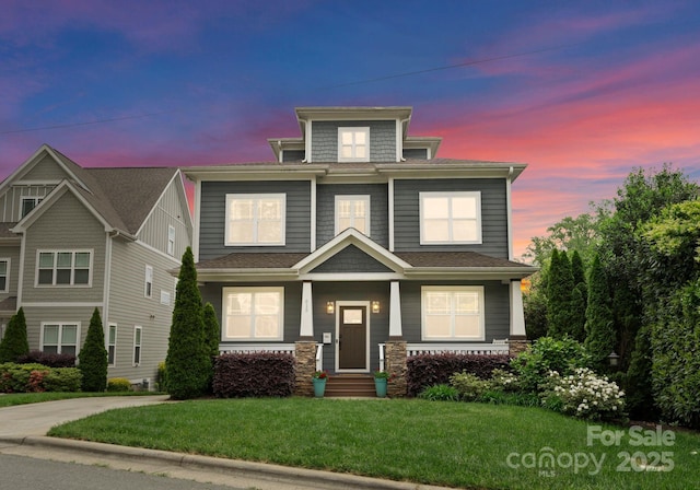 american foursquare style home featuring a lawn and stone siding