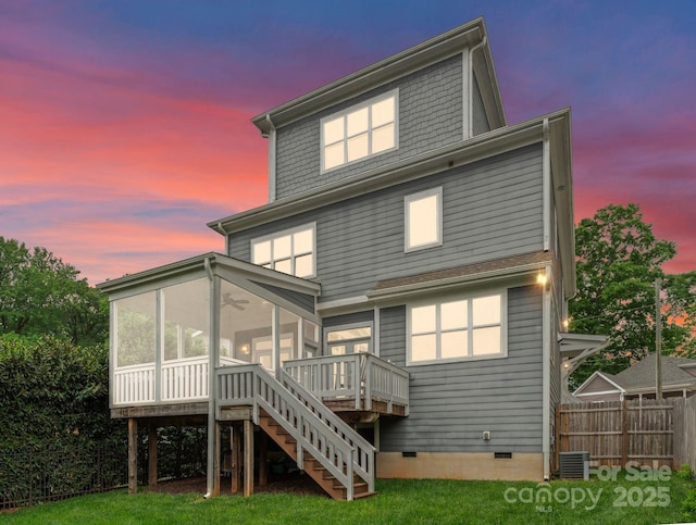 back of house at dusk featuring fence, central AC unit, a sunroom, crawl space, and stairs