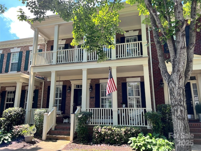 view of front of house with a balcony, brick siding, and covered porch