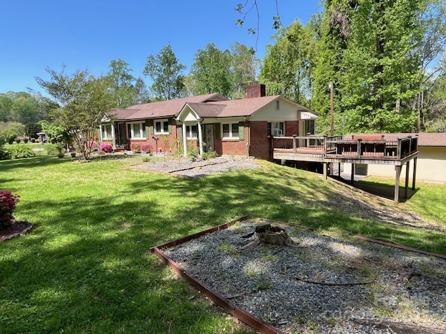 back of house featuring brick siding, a deck, a chimney, a yard, and a fire pit