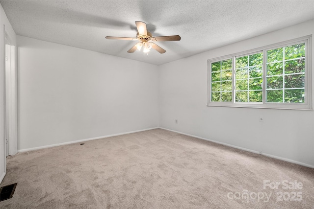 unfurnished room with carpet, ceiling fan, visible vents, and a textured ceiling