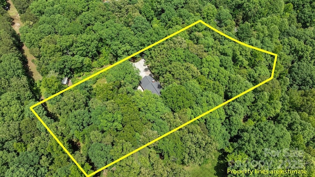 aerial view of property and surrounding area featuring a heavily wooded area and property parcel outlined