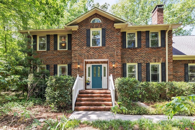 view of front of property with a chimney and brick siding
