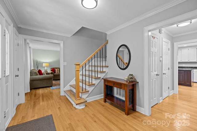 stairway with wood finished floors, ornamental molding, and baseboards