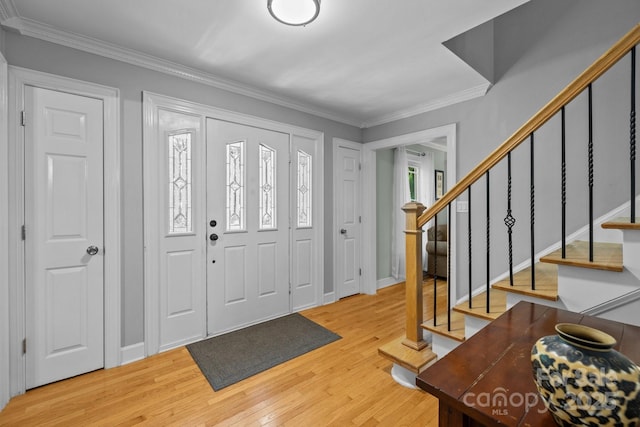 entryway featuring light wood finished floors, crown molding, stairway, and baseboards