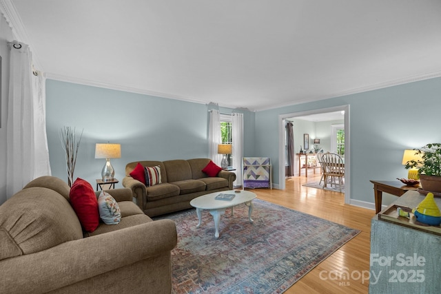 living room with ornamental molding, light wood-type flooring, and baseboards