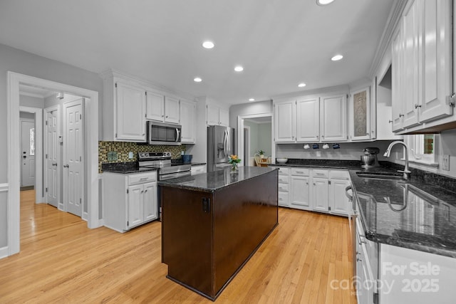 kitchen with stainless steel appliances, a sink, white cabinets, light wood finished floors, and recessed lighting