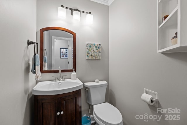half bathroom featuring toilet, crown molding, and vanity