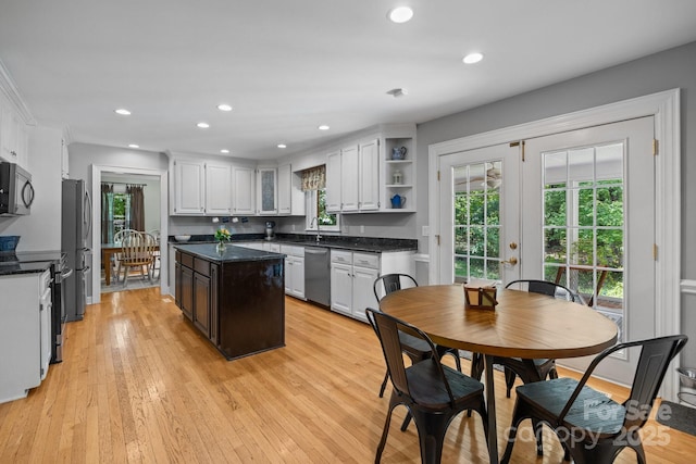 kitchen featuring stainless steel appliances, a center island, light wood-style floors, white cabinets, and open shelves