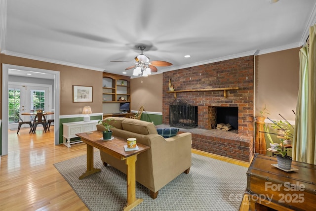 living area featuring a ceiling fan, light wood-style floors, a fireplace, crown molding, and recessed lighting