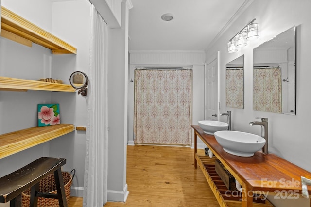 full bath with wood finished floors, ornamental molding, baseboards, and double vanity