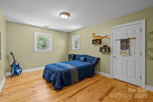 bedroom with wood finished floors, multiple windows, and baseboards