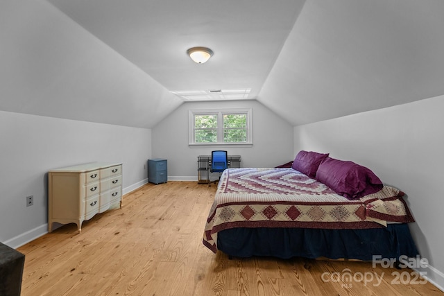 bedroom with light wood-style flooring, vaulted ceiling, and baseboards