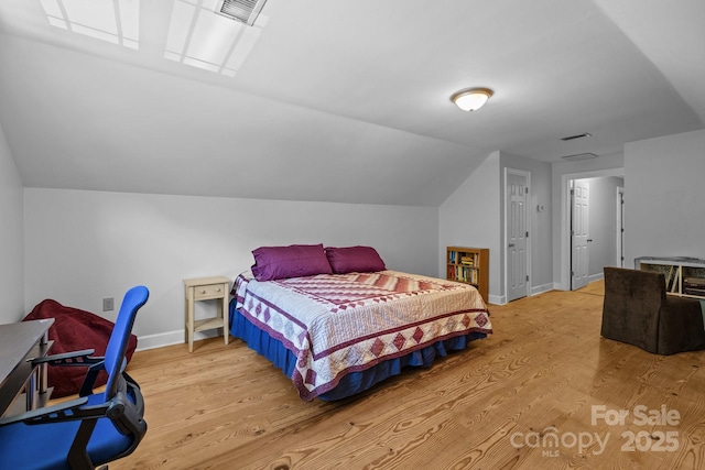 bedroom featuring wood finished floors, vaulted ceiling, and baseboards