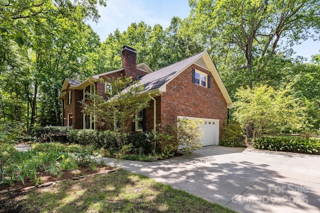 view of side of property with brick siding, driveway, a garage, and a chimney